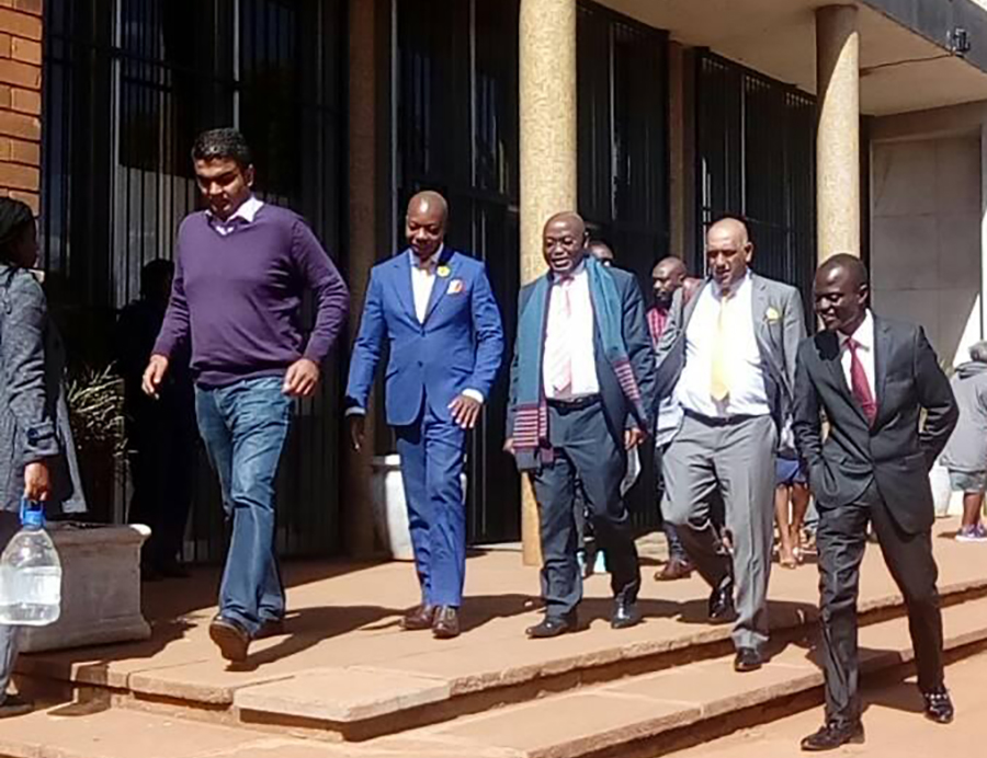 Trial ... Psychology Maziwisa (in blue suit) and Oscar Pambuka (far right) leave court with their lawyer Jonathan Samukange (centre)