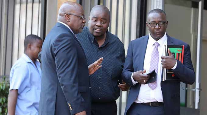 Wicknell Chivhayo chats to his lawyers Advocate Lewis Uriri (right) and Mr Wilson Manase at the court yesterday